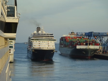 The Zuiderdam going astern with a container ship on the portside and the Grandeur of the Seas on the starboard side.